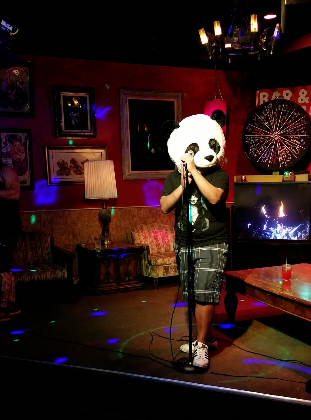 Singer in a panda mask performing karaoke at a bar venue night